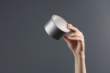 Hand holding duct tape on gray background