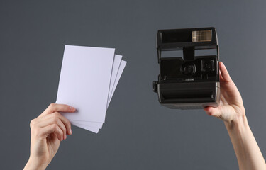 Female hands holds retro instant camera and blank photographs on dark background. Photographer, traveler. Template for design