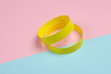 Yellow paper bracelets on pink blue background