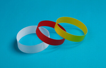 Red, yellow and white paper bracelets on a blue background