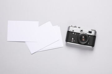 Retro camera with blank white photographs on gray background. Creative layout, mockup, template for design