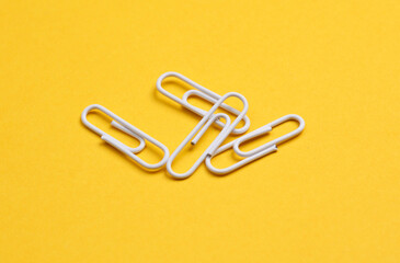 White paper clips on yellow background