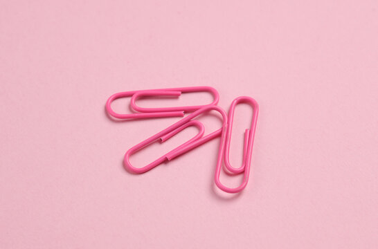 Pink paper clips on pink background