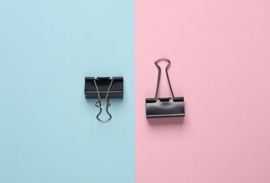 Black binder paper clips on a blue-pink background. Business concept