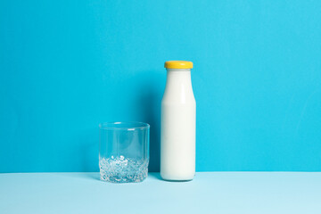 Bottle of yogurt and glass on a blue background
