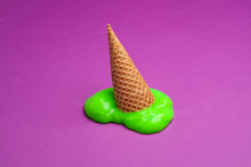 Waffle cone with green slime on a purple background. Minimal halloween layout