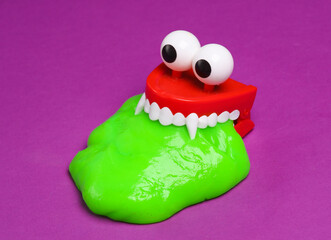 Toy Monster jaw with green slime on a purple background. Minimalism halloween layout