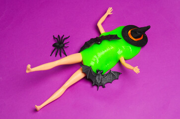Doll with green slime, witch hat, spider, bats on a purple background. Minimalism halloween layout