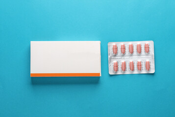 Medicine layout. Template for design. Box with blister of pills on a blue background - obrazy, fototapety, plakaty