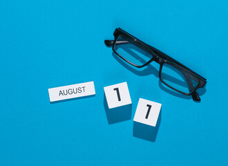 White cube calendar with date august 11 with eyeglasses on blue background. Deadline, business concept