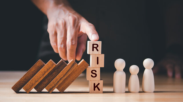 Business Crisis, Risk Management Concept. Hand stopping wooden domino protect crisis effect, falling to family. Concept of Business Crisis, Risk, Management, Assessment, Insurance, Security, Financial