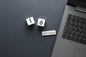 White wooden block calendar with date september 16 and laptop on gray background. Business, deadline, planning