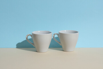 Two ceramic coffee cups on a blue-beige background. Creative layout. Minimal drinks still life