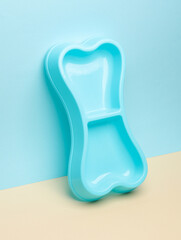 Empty dog bowl in the shape of a bone on a pastel background