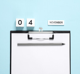 Business concept, planning, deadline. Block Calendar with date november 04 and clipboard on a blue background.