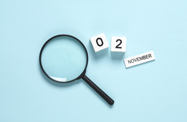 Business concept, planning, deadline. Calendar with the date november 02 and a magnifier on a blue background.