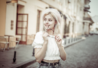 Portrait of a charming young woman in a beret and glasses on European street