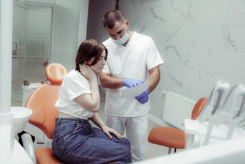 Professional doctor dentist shows a picture of teeth to a woman sitting in a chair to a patient