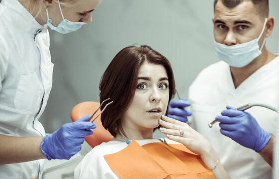Young scared woman examined by dentist at the dental clinic. Fear of Teeth Healing