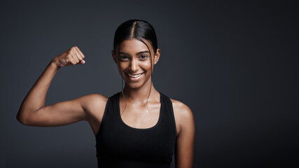 Portrait, smile and woman flexing bicep in studio isolated on a black background mockup space. Strong, happy and female athlete with muscle, arm strength and bodybuilder ready for fitness workout.