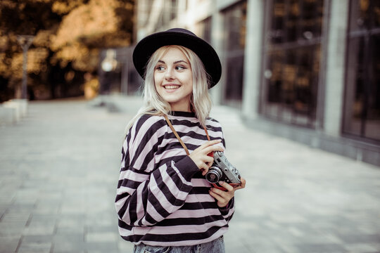 Charming hipster girl in hat with retro camera outdoors