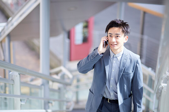 20代日本人ビジネスマンがスマートフォンを使用して仕事をしている春のイメージ