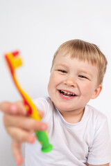 Child with a toothbrush on a white background brushes his teeth and smiles close-up, the concept of caring for children's milk teeth, personal hygiene procedure.