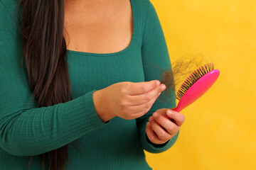 Woman's hands take a hairbrush with many fallen hairs after brushing for alopesia, anemia or...