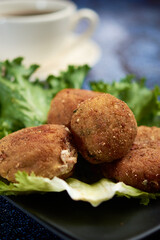 Breaded potato nuget, with orejona lettuce, with dry chile sauce, a coffee in the background