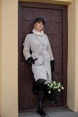 Photography of young woman with black cap and white flowers looking at the camera big beautiful eyes near door 