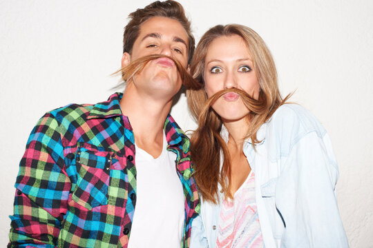 Silly portrait of couple with hair moustache, funny face and gen z fashion with university culture in youth. Happiness, woman and hipster man in crazy picture at fun college event on wall background.
