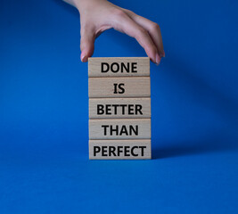 Done is better than Perfect symbol. Wooden blocks with words Done is better than Perfect. Beautiful blue background. Businessman hand. Business and Done is better than Perfect concept. Copy space.