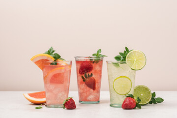 Strawberry, mojito, grapefruit lemonade with ice on beige background. Summer refreshing drinks