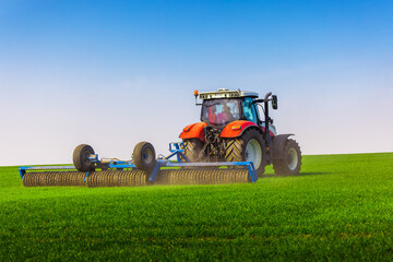 Tractor with a roller tillage on spring field. Soil rolling supports germination and is the basis...