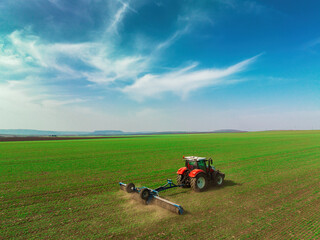 Tractor with a roller tillage on spring field. Aerial view of Soil rolling supports germination and...