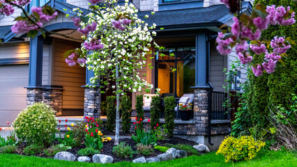 Fototapeta na wymiar Luxury front yard house with colorful blooming flowers and shrubs. Beautiful house in residential neighborhood, Vancouver Canada. 