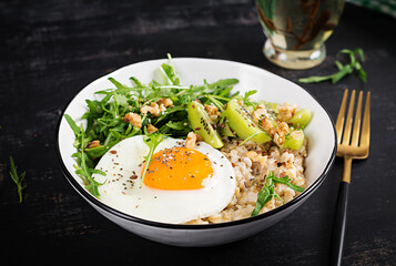 Breakfast oatmeal porridge with roasted eggs, kiwi, arugula and flax seeds. Healthy breakfast to lower cholesterol.