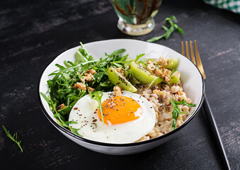Breakfast oatmeal porridge with roasted eggs, kiwi, arugula and flax seeds. Healthy breakfast to lower cholesterol.