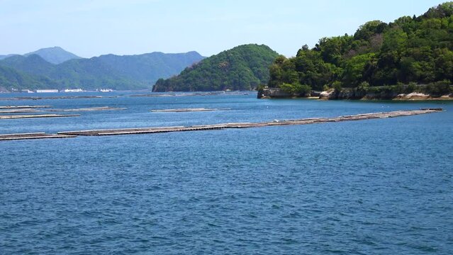 瀬戸内海、広島湾に浮かぶ牡蠣養殖筏と島の風景を船から移動撮影  4K  2023年4月23日 宇品島・似島付近にて撮影