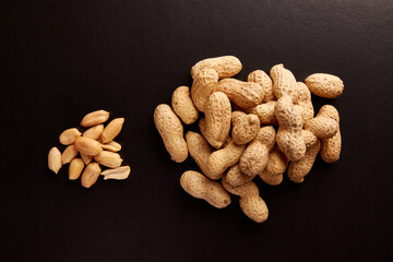 A pile of unshelled peanuts on a black background. An ingredient for preparing tasty and healthy dishes.