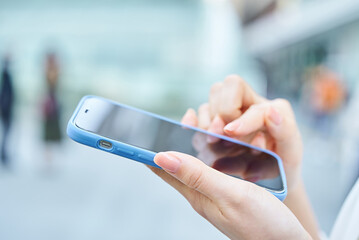 街角でスマートフォンを使う女性の手元