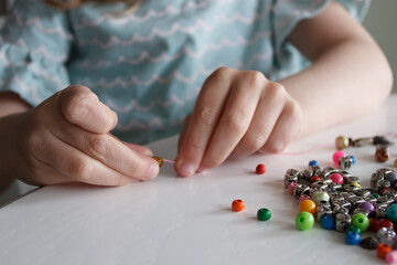 Process of making a bracelet from a thread and colored beads, concept of hobby