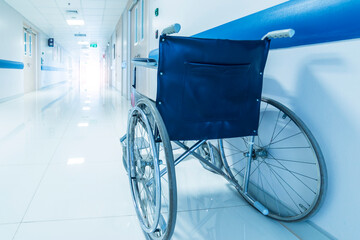 Blue tone of empty wheelchair on hospital or clinic corridor or hallway with light tunnel.Bright clean with blur background.Wheel chair in orthopedic unit for patient.Medical or insurance concept.