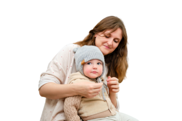 Mother puts a warm scarf on the toddler baby, isolated on a white background. Woman mom dressing warm clothes on child for winter walk in cold weather. Kid aged one year and three months