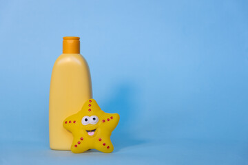 Yellow layout of a children's cosmetic product with a place for a logo and funny toy on a blue background. Baby shampoo, shower gel or body lotion. Space for text