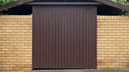 wooden gate with vertical slats against brick wall