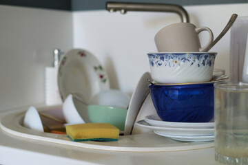 Dishwashing duty: A sink overflows with dirty dishes, as a lone sponge stands ready for action. psychological impact of clutter and mess on mental health.
