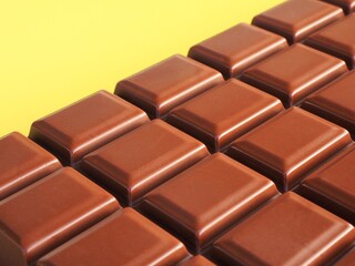 Close up of a milk chocolate bar on a yellow background