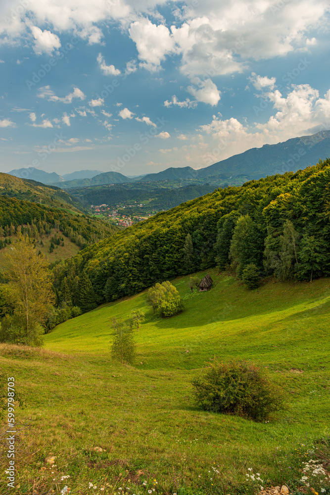 Wall mural Rural idyllic landscape of the small villages in the Rucar-Bran mountain area, Brasov, Romania, scattered on the wooded hills, with the Bucegi mountains in the background, in wonderful springtime day