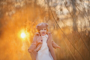 Baby portrait. Two year old girl. Girl in a coat and beret. Sunset. The baby smiles. Laughter. Early spring. Autumn. Vintage. Fashion girl. An evening walk, Sweet baby